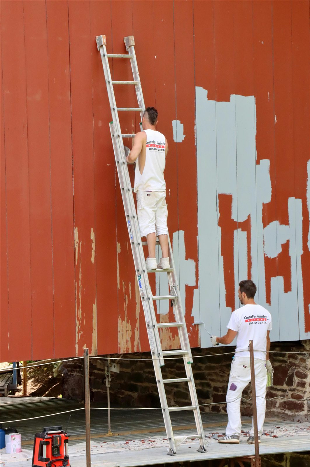 Exterior painting work near red siding and outdoor trim